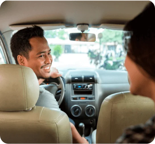 A man smiling drives a person in a car to a certain study location destination